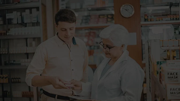 Pharmacist helping a customer choose medication inside a retail pharmacy